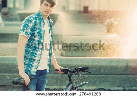 Young hipster style man posing with bicycle on the street sport style picture handsome guy  ready for trip