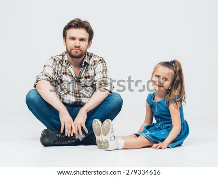 Father with daughter sitting on floor in jeans and plaid shirt