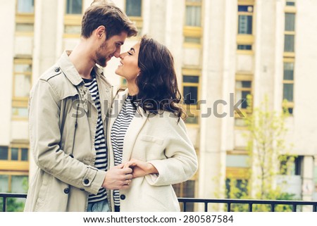 Fashion lovely couple posing in the old part of town. Young man and sensual brunette outdoor portrait in stripes  dress. Outdoors, lifestyle.