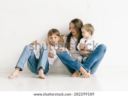 Family mother with children studio portrait full length sitting in jeans on white background