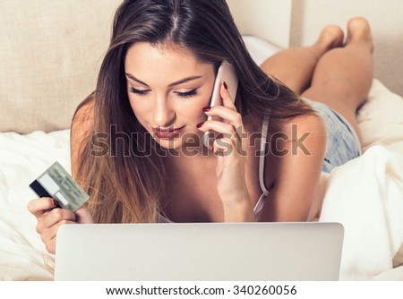 Woman with credit card and laptop notebook buying online mobile phone