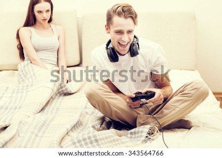 Man is playing playstation computer game woman girlfriend is angry for him