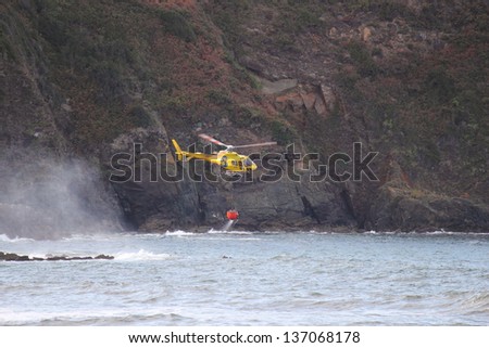 CUDILLERO, SPAIN - OCTOBER 8: Fire rescue helicopter refill bucket in the sea, goes to a fire in Cudillero,  on October 8, 2011 in Cudillero, Spain