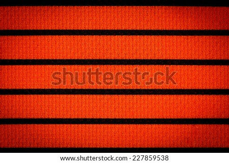Orange sportswear fabric with black stripes texture closeup photo background.