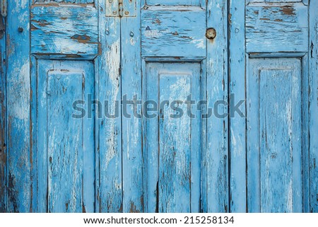 Closeup detailed texture of bright blue paint peeling off of an old wooden door. Background texture is from a door in Mykonos, Greece.