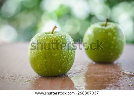 green apple on the table outside the home with natural light. according to the concept of freshness, health food and drinks or restaurants, supermarkets, green apple based products.