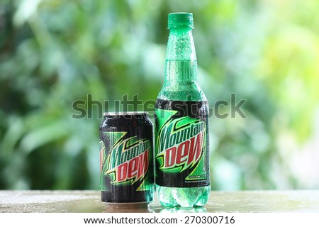 SABAH, MALAYSIA - April 16, 2015: Bottle and can of Mountain Dew drink with blurred impression of a garden. Mountain Dew was introduced in 1940.