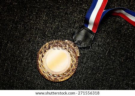 Gold medal on rough fabric colored black. Concept for winning or success