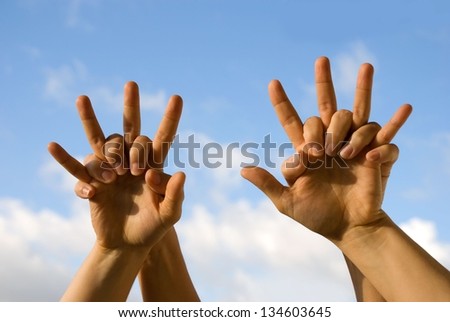 four hands cheering in front of the sky