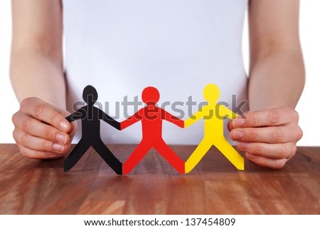 hand holds paper chain people in the color of germany, isolated