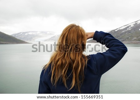 A Woman in Outdoor Look Watches at Glaciers in the Mountains