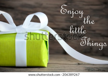 Green Gift with the Saying Enjoy the Little Things on wooden Background
