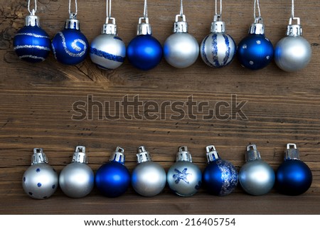 Two Lines of Blue and Silver Christmas Balls, some with Decoration, on Wood with Copy Space for Your Text, Christmas or Winter Background