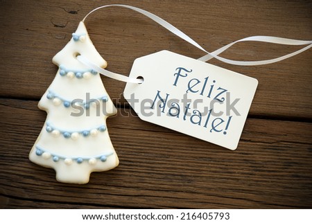 The Blue Portuguese Words Feliz Natale, which means Merry Christmas, on a white Label with a Christmas Tree Cookie