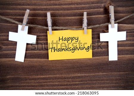 Yellow Label with Happy Thanksgiving Greetings Hanging on a Line with two white Crosses, Wooden Background