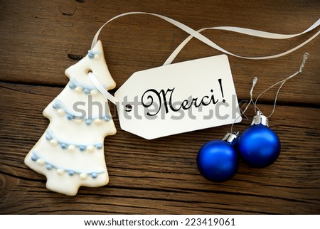 Christmas Background with Christmas Tree and Decoration and a Label with the French Word Merci which means Thanks