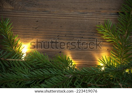 Wooden Background with Copy Space and Fir Tree Branches as a green Winter or Christmas Frame, lighted with Fairy Lights