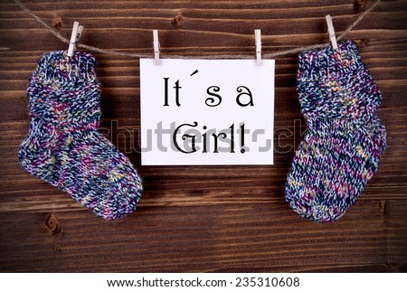 Pink Tag Or Label With Two Baby Socks On A Line With Its a Girl On Wooden Background, Vintage, Retro And Old Fashion Style With Frame
