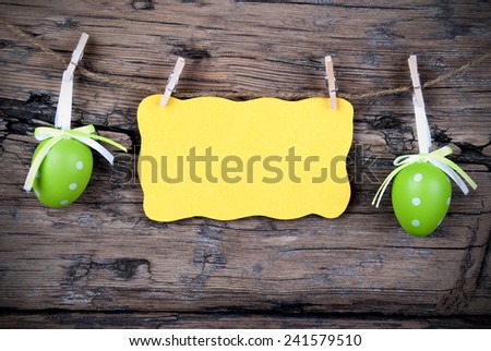 Yellow Easter Label With Copy Space Or Your Free Text Here Hanging On A Line With Two Green Easter Eggs On Wooden Background, Vintage,  Old Fashion, Rustic Or Retro Style And Frame