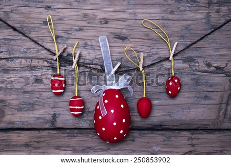 Easter Eggs And One Big Dotted Red Easter Egg With A Loop And Ribbon Hanging On A Line Which Are Dotted And Striped On Brown Wooden Vintage Or Rustic Background For Easter Greetings And Happy Easter
