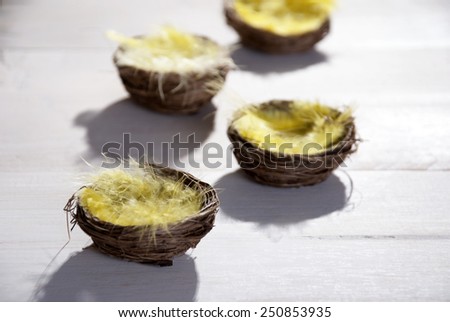 Four Easter Baskets Or Nests With Yellow Feathers in Sunny Light With Copy Space Free Text Or Your Text Here For Happy Easter Greetings Or Easter Decoration Close Up Or Macro Wooden Background
