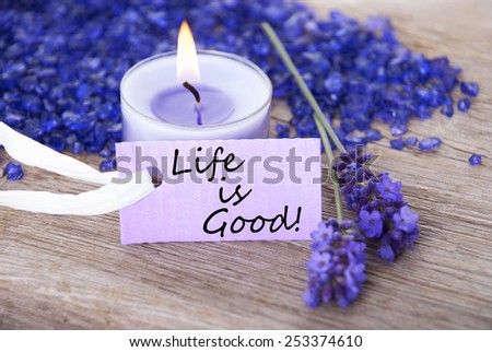 Purple Label With Candle Light And Lavender Blossoms With English Life Quote Life Is Good Wooden Background With White Ribbon