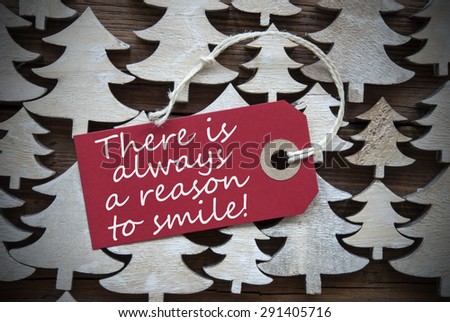 Red Christmas Label With Ribbon On Wooden Christmas Trees Background. Vintage Style. Label With English Quote There Is Always A Reason To Smile For Christmas Or Season Greetings.Close Up Or Macro