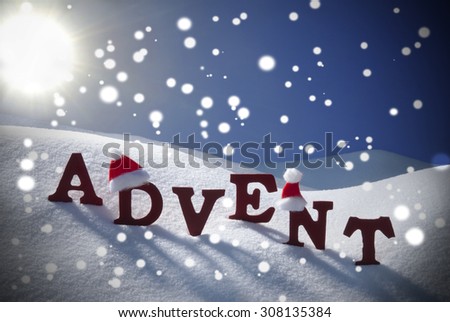 Red Wooden Letters With Santa Hat Building German Word Advent Means Christmas Time Or Season. Snow And Snowy Scenery With Snowflakes.Wooden Background. Sunny Christmas Atmosphere With Sun And Blue Sky