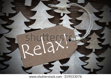 Brown Christmas Label With Ribbon On Wooden Christmas Trees Background. Vintage Style. Label With English Text Relax For Christmas Or Season Greetings.Close Up Or Macro