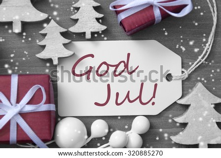 Black and White Close Up Of Label With Ribbon,Red Gift,Present, Ribbon And Tree With Snowflakes. Christmas Decoration Or Card On Wooden Background. Swedish Text God Jul Means Merry Christmas
