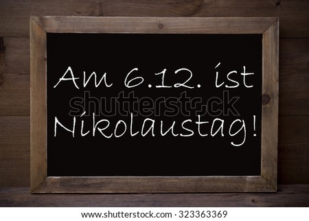 Brown Blackboard With German Text Am 6.12 Ist Nikolaustag Means St. Nicholas Day As Christmas Greeting Card. Wooden Background. Vintage Rustic Style.