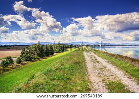 Gravel road along the shore of the lake with blue water in Polish.