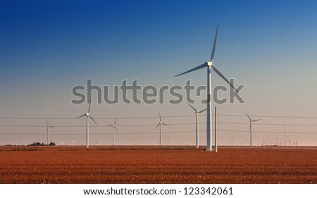 Wind Turbine farm in cotton fields in West Texas.   High Voltage power lines also running through image