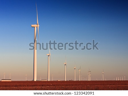 Wind Turbine farm located in a cotton field in West Texas.  The cotton has been harvested as is bailed for pick up.