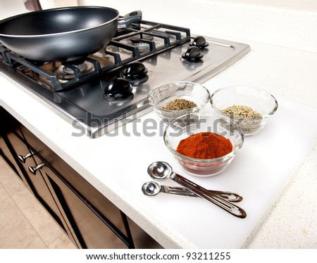 Herbs and spices used in cooking preparation.  Gas range with wok shown in background.