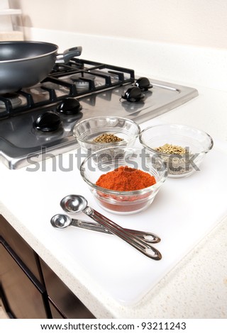 Herbs and spices used in cooking preparation.  Gas range with wok shown in background.