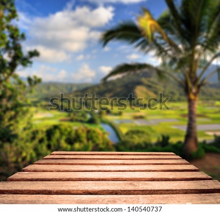 Old weather worn plank table top with tropical Hawaii in background.  Focus is on planks in foreground