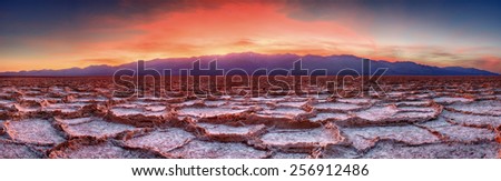 Panorama of a vivid sunset at Badwater Flat in Death Valley National Park.   The sun sets behind Telescope Peak in the background