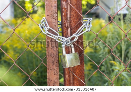 Rusted gate is lock with a chain and padlock