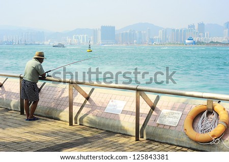HONG KONG - MAY 22: Unidentified man fishing on embankment on May 22, 2012 in Hong Kong. With population of 7 million people, Hong Kong is one of the densely populated areas in the world