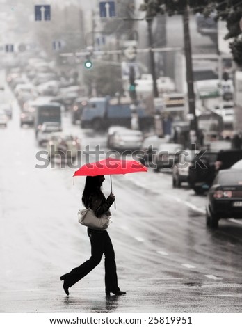 women with red umbrella cross the street in the rain
