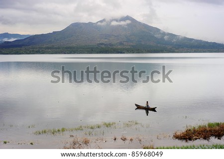 BALI ISLAND, INDONESIA - APRIL 10: Man fishing in a caldera lake of Batur volcano on April 10, 2011 in Bali, Indonesia. Batur is the most active volcano Bali and one of Indonesia\'s more active ones