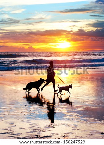 Man with a dogs running on the beach at sunset. Bali island, Indonesia