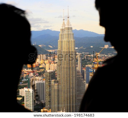 KUALA LUMPUR, MALAYSIA -  JUNE 15, 2012: People looking to Petronas Twin Towers from viewpoint of Kuala Lumpur Tower ( Menara). The Petronas Towers are the tallest twin buildings in the world.