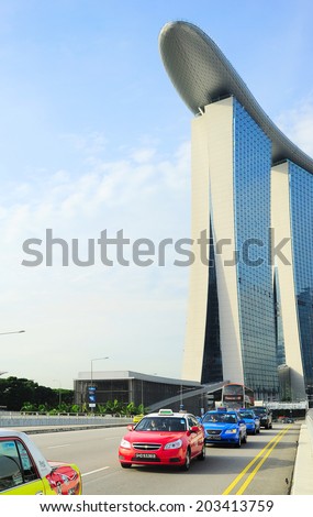 SINGAPORE - MAY 09, 2013 : Taxi cab driving by the road in front of Marina Bay Sands hotel in Singapore. The government will spend SGP$14 billion to improve Singapore\'s road infrastructure