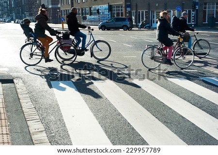 AMSTERDAM, NETHERLANDS - FEB 26, 2014: Unidentified people crossing the street by bicycle. It is one of the most cycle-friendly cities in the world. 58% of the citizens uses daily a bicycle.