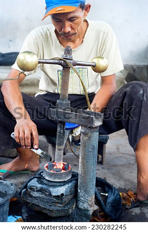 PROBOLINGO, INDONESIA- APRIL 22, 2012: Unedentified  Indonesian man repairs motorcycle inner tube