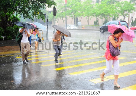 HONG KONG - MAY 20, 2013: People crossing the road in the rain.  With a land mass of 1,104 km and population of 7 million people, Hong Kong is one of the most densely populated areas in the world