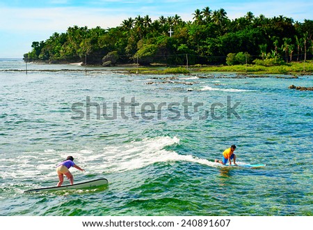 SIARGAO, PHILIPPINES - MAY 11, 2013 :Young people learning to surf at Cloud 9 surfpoint in Siargao, Philippines.  In 2011 3.9 million tourists visiting the country.