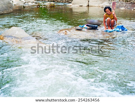 SAGADA, PHILIPPINES - MARCH 25, 2012:  Philippines woman washing clothes on the river in traditinional way. More than one-quarter of the population of Philippines fell below the poverty line